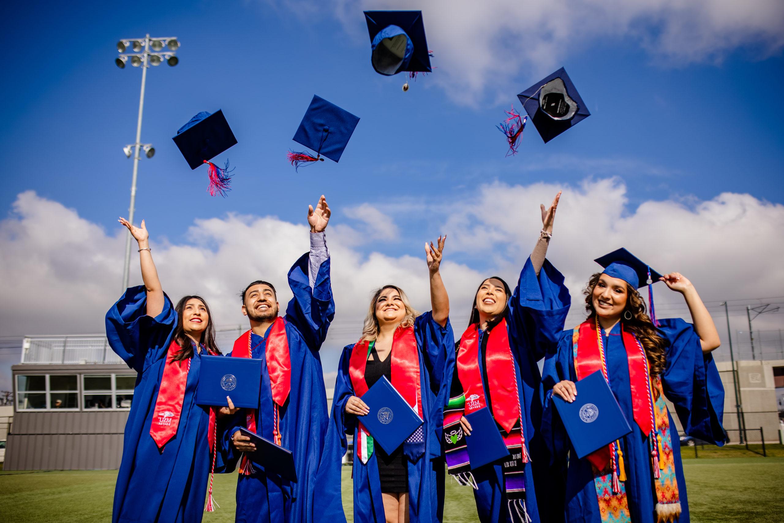 MSU Denver students celebrating graduating by throwing their graduation caps in the air